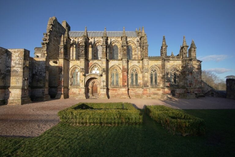 Ornate stonework of the Rosslyn Chapel and surrounding green hedges
