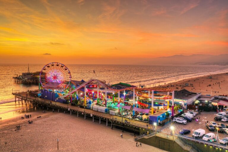 The lively Santa Monica Pier with rides, a ferris wheel, and a fun fair at sunset 