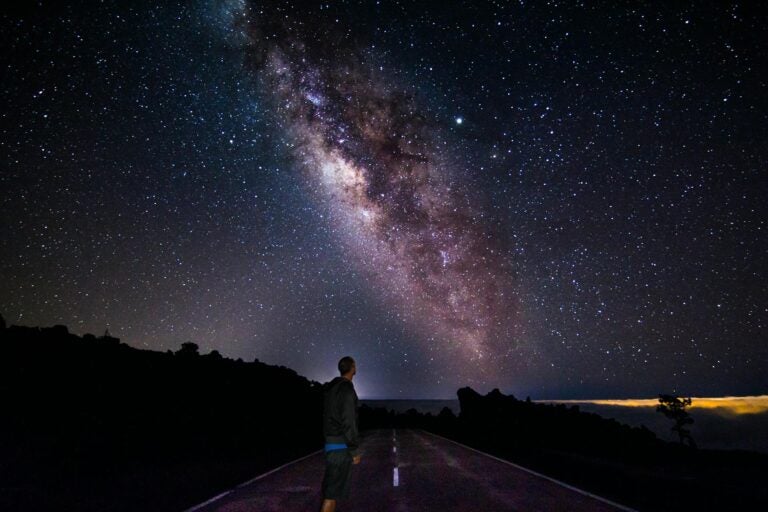 young man watching the starry la palma night in the middle of the road