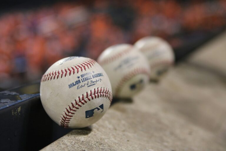 Three white and red Major League baseballs lined up