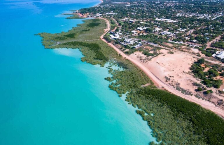 turquoise blue waters and land separated by greenery 