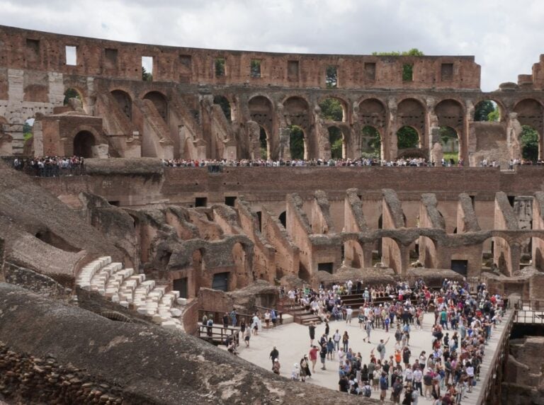 The rustic structure of the colosseum stands tall as people explore its interiors
