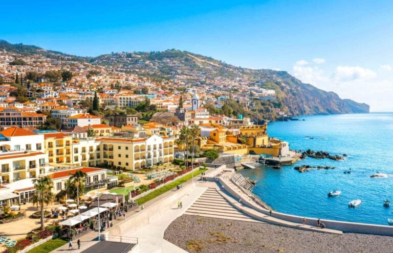 aesthetic white, red, and pastel yellow houses and complexes on Madeira Island's shore, a stone's throw from the blue waters