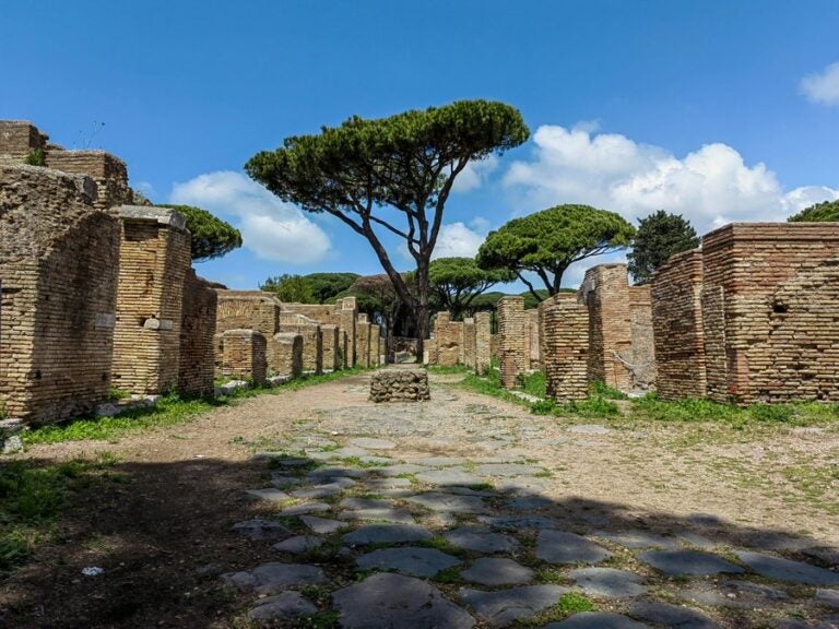 stone structures line each side of a pathway leading up to trees