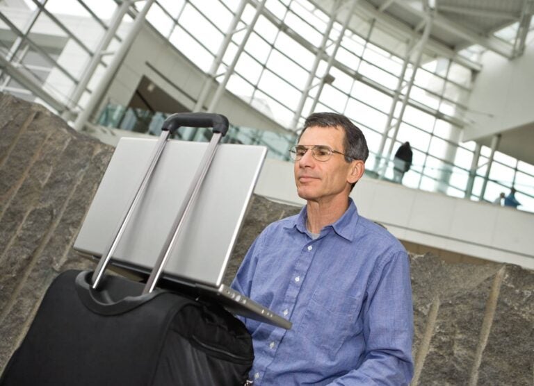 man sitting with his laptop on an airport
