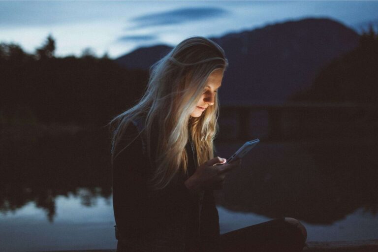 A woman sitting in nature and looking at her phone