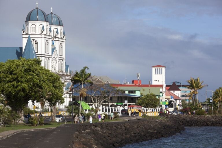 The shoreline of the town of Apia, Samoa, with people walking along the shore's path.