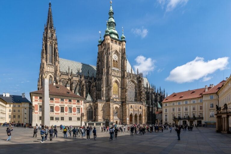 Prague Castle, Prague and the plaza surrounding it with people walking along the street.