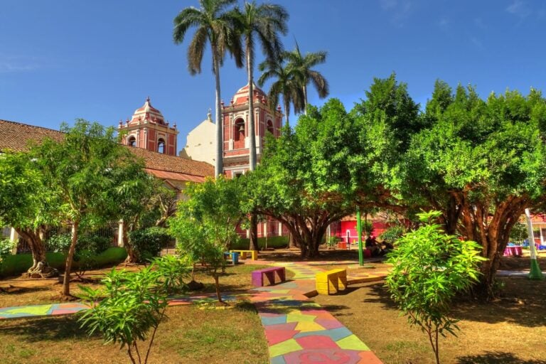 A church surrounded by trees, a colorful path, and greenery in the city of Granada, Nicaragua.