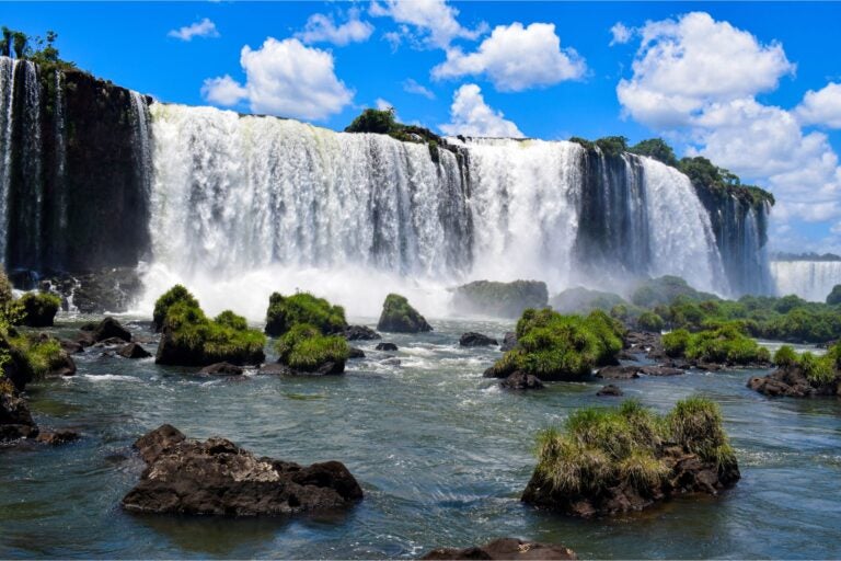 The Brazil side of Iguazu Falls amid a blue cloud-filled sky.