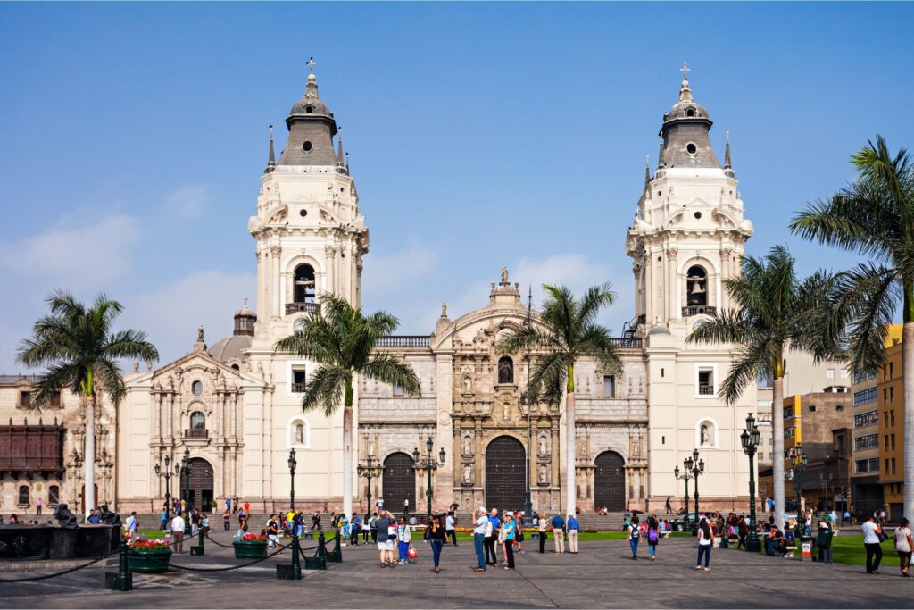 Central plaza in Lima, Peru during the day with people standing in front of a church.
