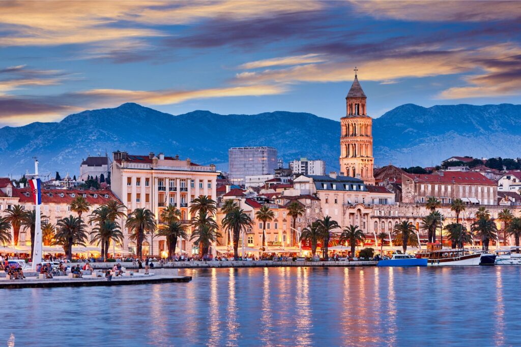 The main promenade of Split, Croatia in the evening, with mountains in the background.