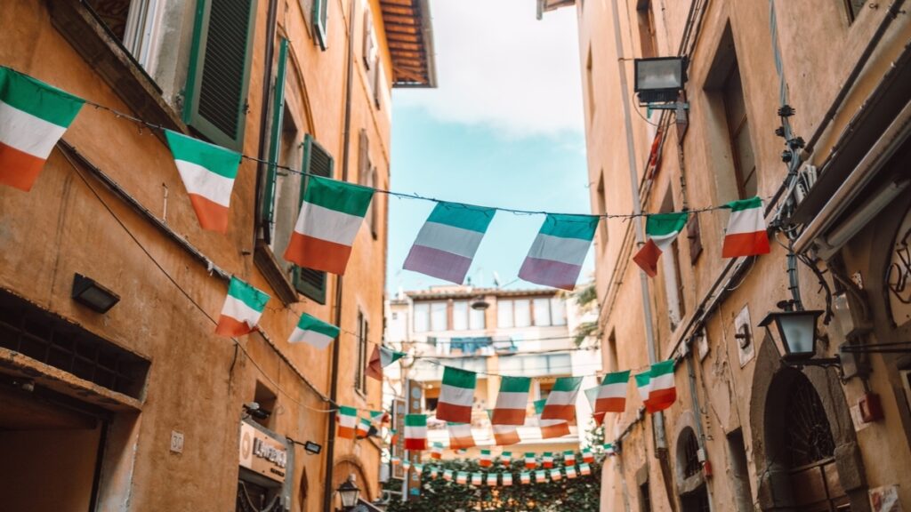 italian flags on a wire between two buildings 