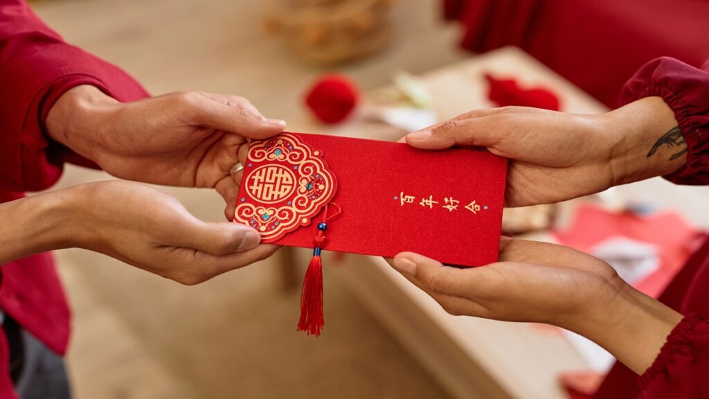 person handing red envelope for the Chinese New Year to another person