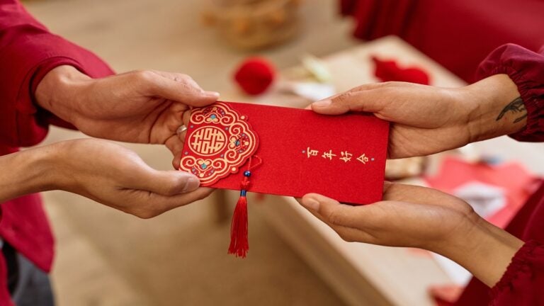 person handing red envelope for the Chinese New Year to another person 