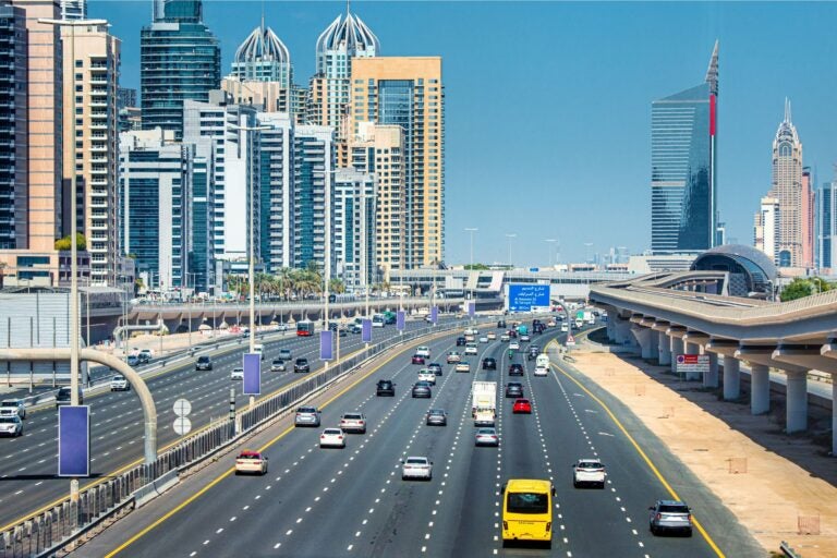 Areial view of Dubai city and highway, with cars driving along all lanes.