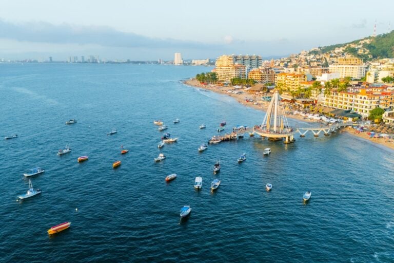 Aerial view of Puerto Vallarta Pier at dusk, with the shoreline in view and boats surrounding the front of the pier.