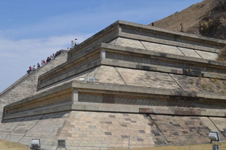 Closeup of the Great Pyramid of Cholula, Mexico and people climbing up the side.