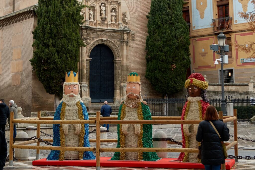 Statues of the Three Kings placed in front of a church with a woman standing in front of one of the statues.