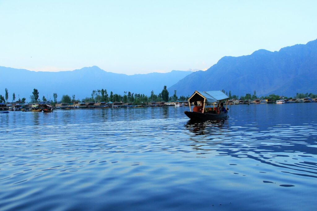 Man riding a boat in the Dal Lake with snowy mountains in the background
