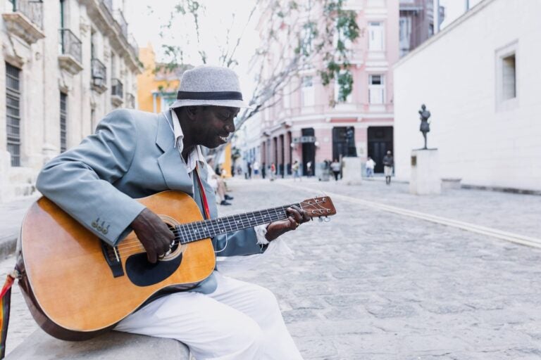 man dressed in a suit playing the guitar in a Cuban street