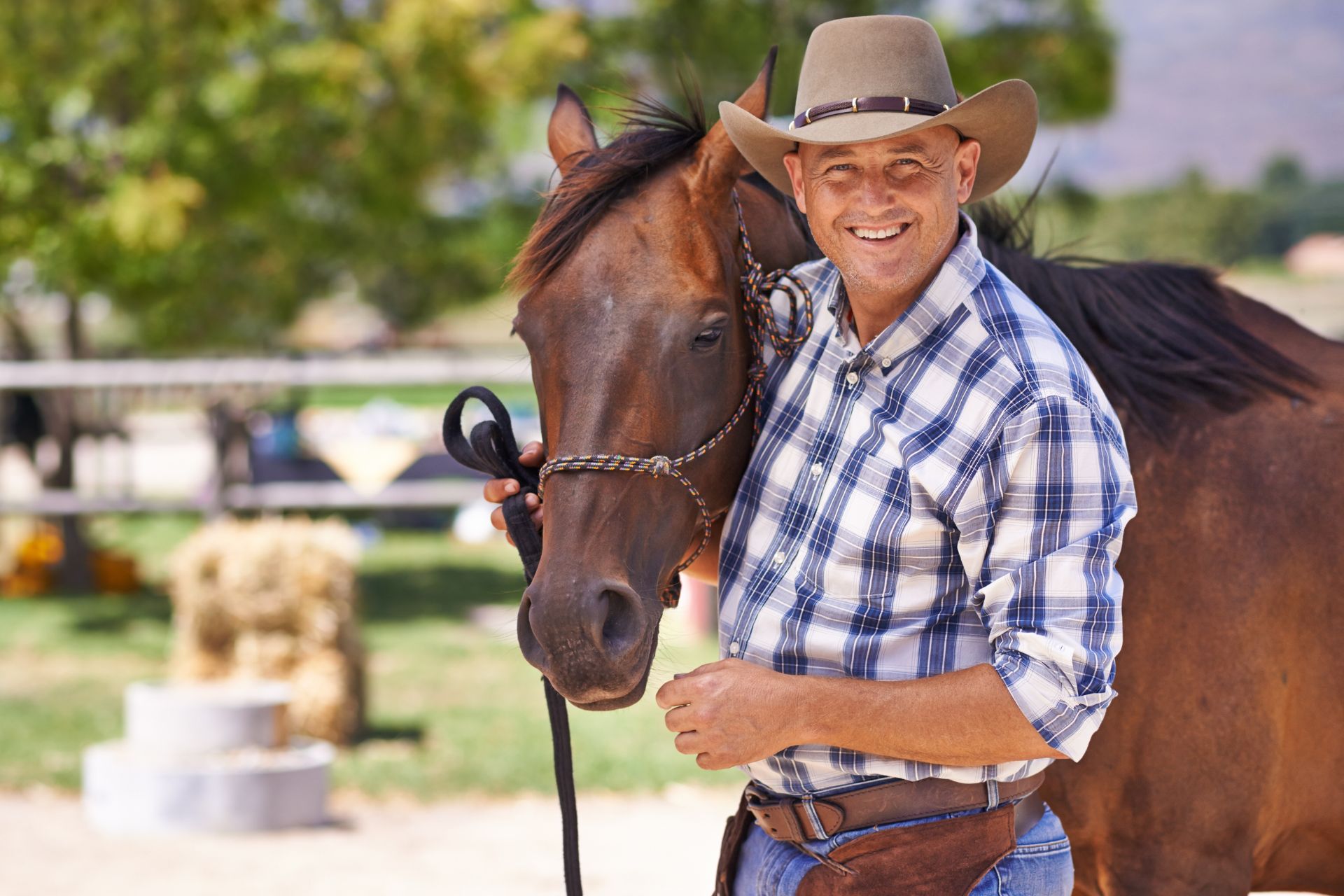 A man in a cowboy hat stands with his horse.
