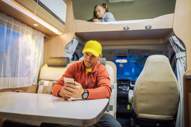 a young man and a girl using their phones in an rv