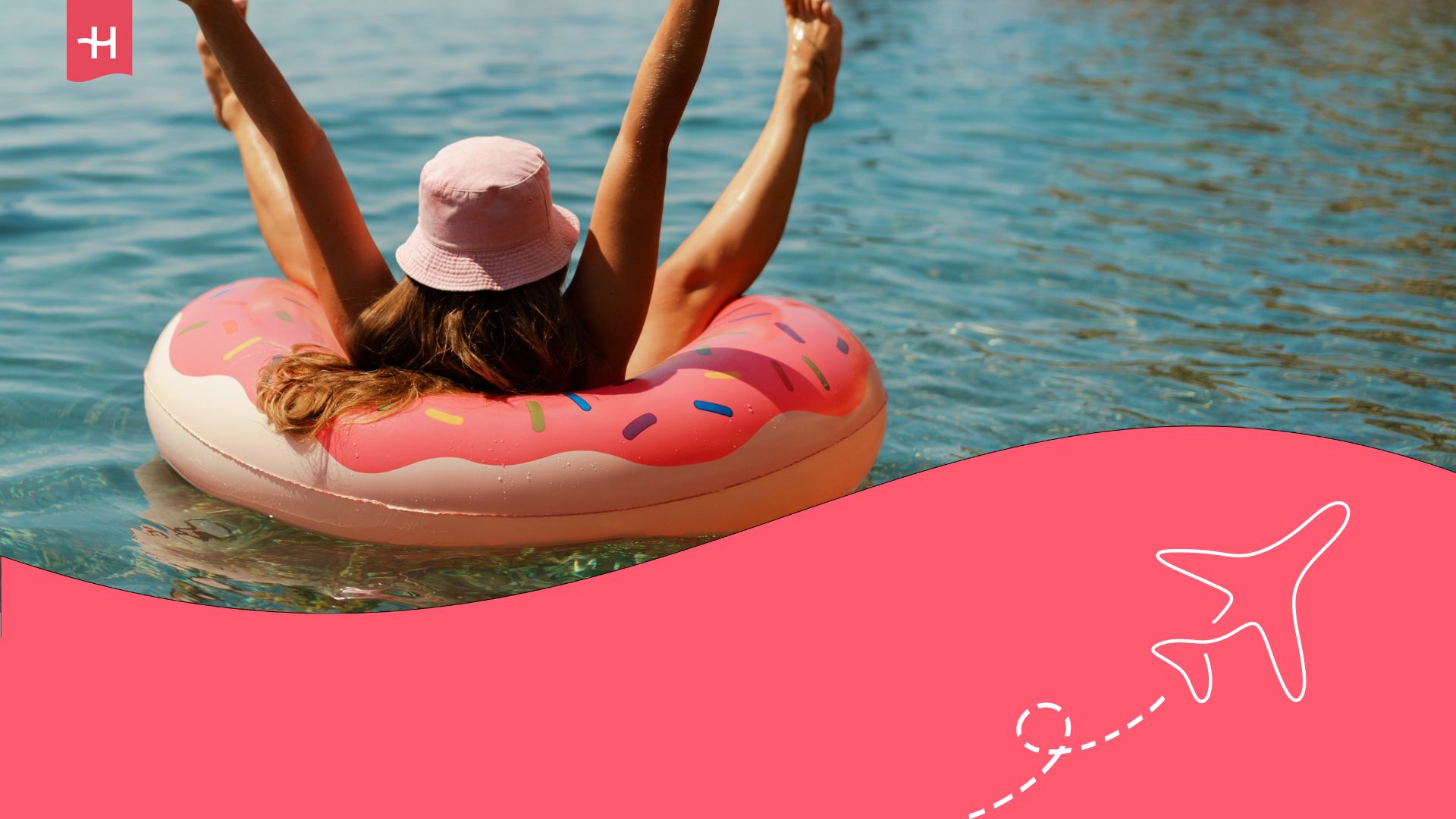 A woman with a straw hat and her arms raised in a lake on a doughnut-shaped floating accessory.