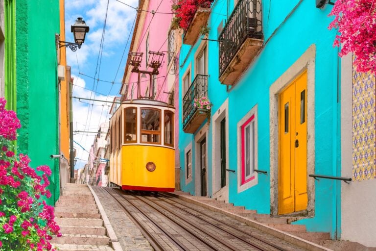 The colourful streets of Lisbon with a tram going up the street.