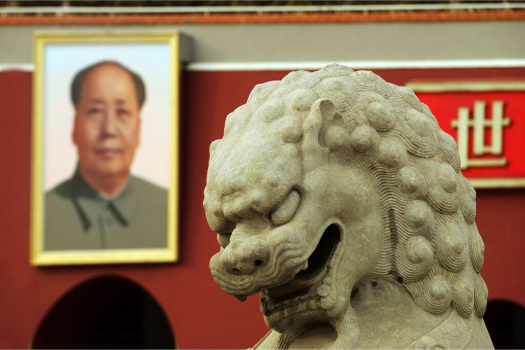 Mao Zedong poster in the background and a statue of a dragon in the middle of the shot.