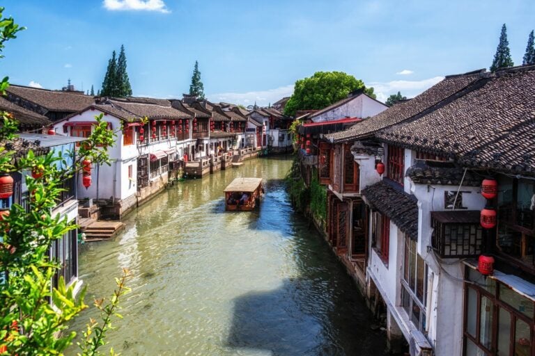 The water town of Zhujiajiao, it's old houses, and a boat sailing down a canal.