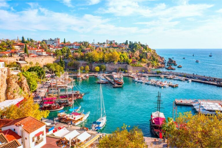 Aerial view of the town of Antalya, with boats docked at the shore and along the pier.