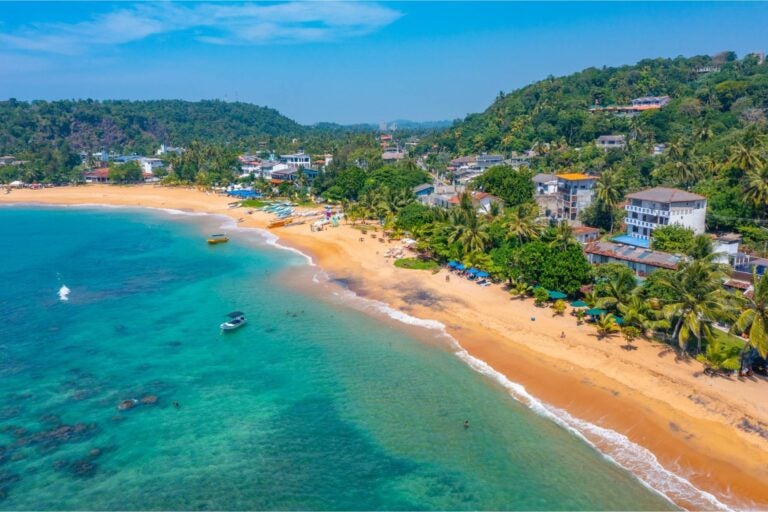 Aerial view of Unawatuna in Galle, with the shoreline, homes, and surrounding mountains.