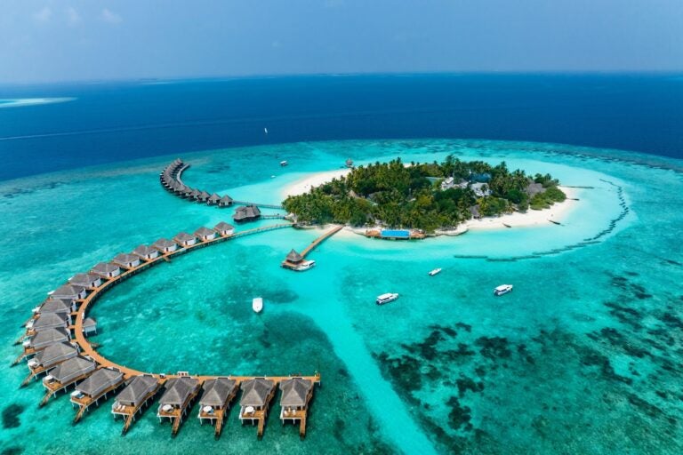 Aerial view of the ocean, boats, and bungalows on the island of Malé.
