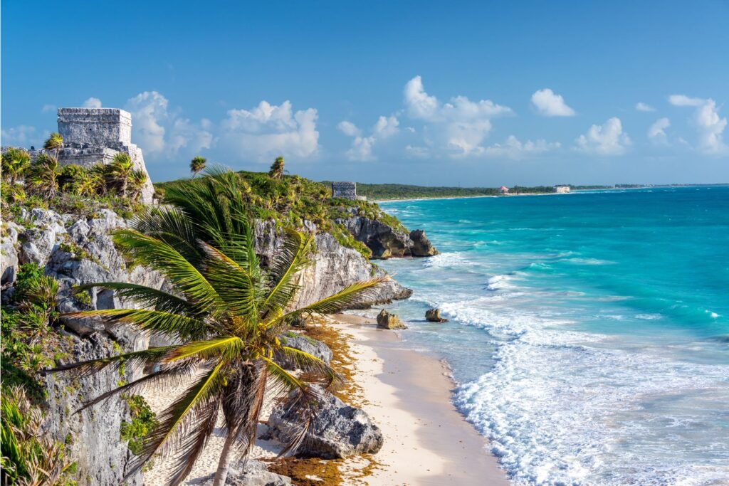 A beach shot of Tulum ruins, sand, and sea