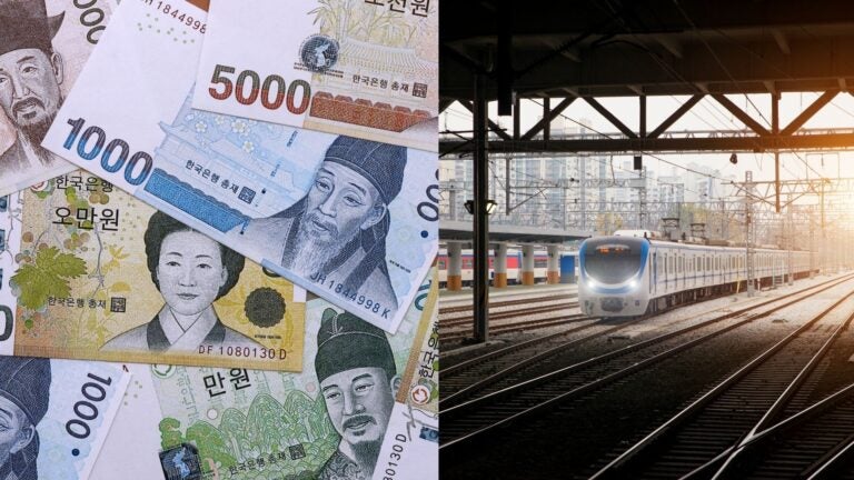 South Korean won banknotes beside a commuter train at a city station.