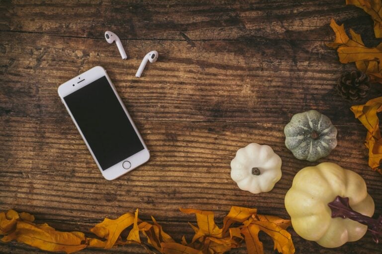 Iphone mobile with airpods and Halloween decorations.
