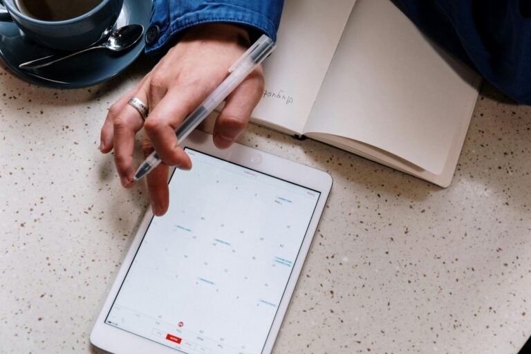 Student hand holding a pen and checking a calendar apps.