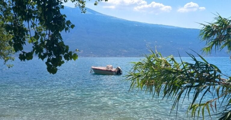 A boat floating in the blue water of Garda Lake.