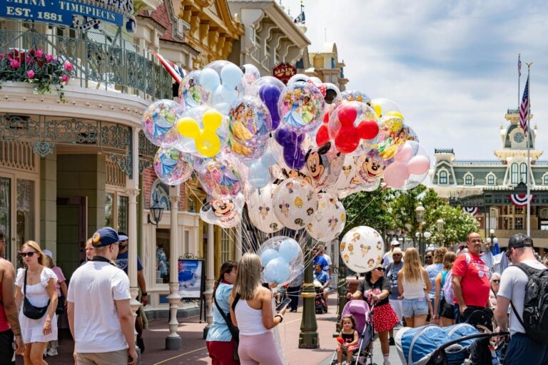 student holding balloons while at Disneyland USA
