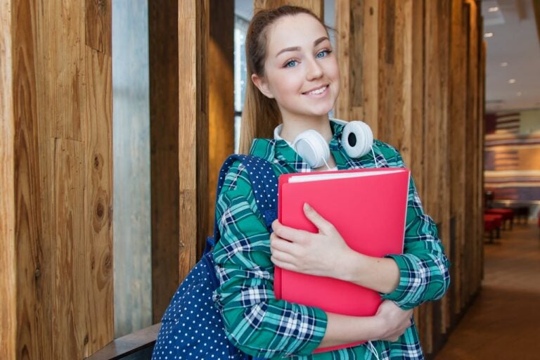 Young female student holding books. Freshman year.