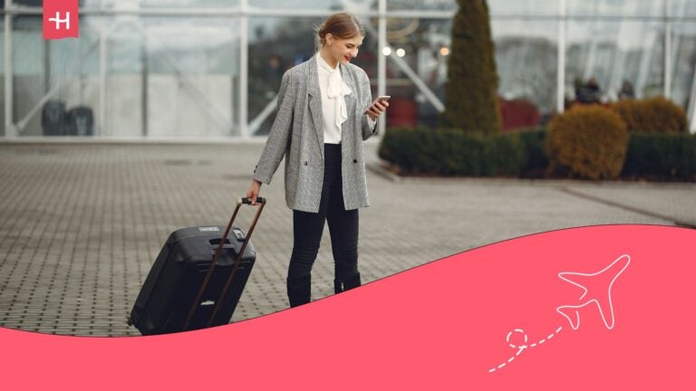 lady working on her phone while walking outside the airport with her trolley bag - digital wellbeing
