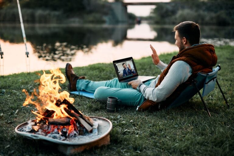 Man talking to his life coach while sitting by the river with a campfire by his side