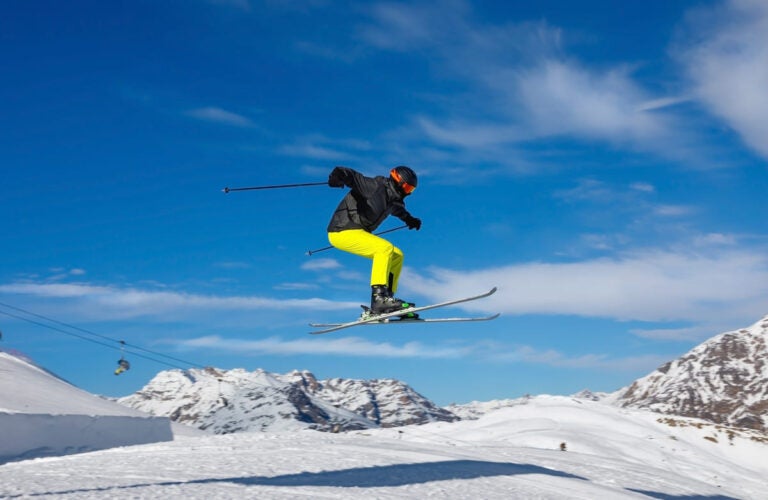 Skier jumps in snow park in the snowy mountains against the blue sky