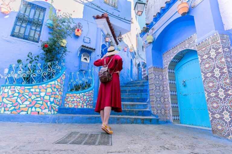 Woman in a red dress close to the iconic Chefchaouen buildings