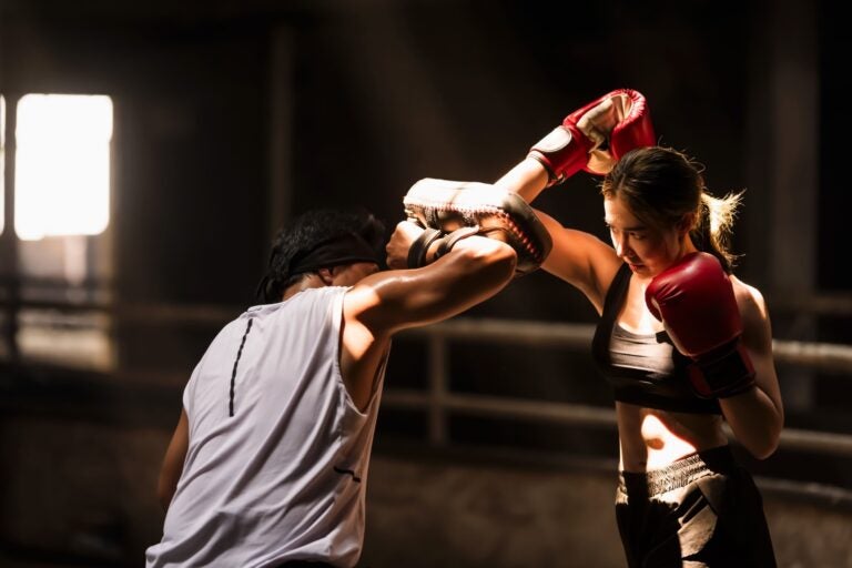 Boxing instructor training a beginner during a one-on-one coaching session at an international gym.

