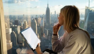 A woman on a tablet looks over a city skyline