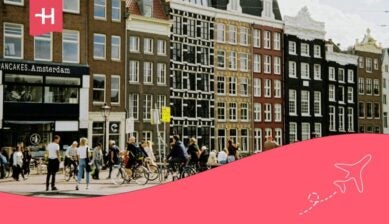 Colourful buildings and people walking and cycling in the city of Amsterdam.