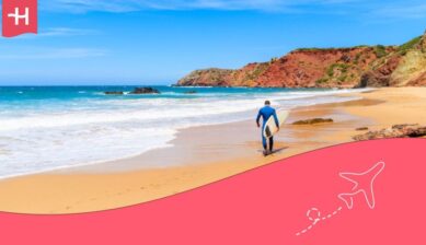 Man with a surfboard in his hand on a beach in Portugal
