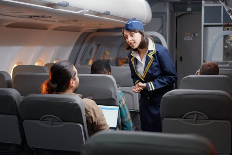 A flight attendant seeing to a the needs of a passenger in-flight
